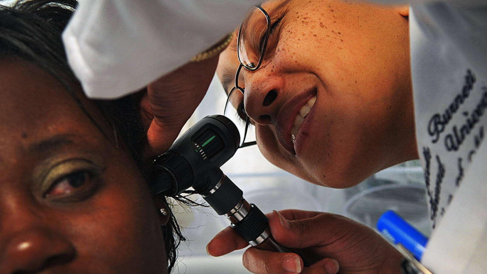 Doctor performing ear exam on patient.