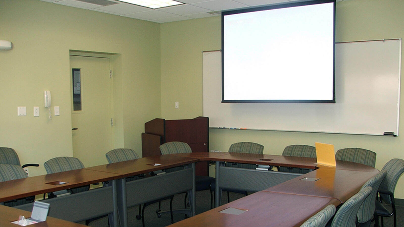 Conference room with an oval desk and chair and projector screen