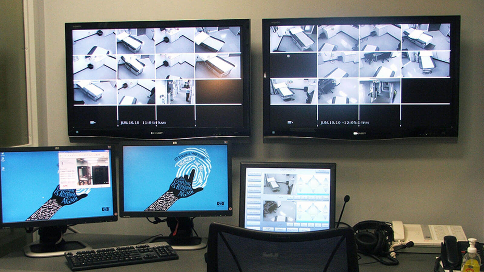 Security and desktop monitors on a desk in front of a chair